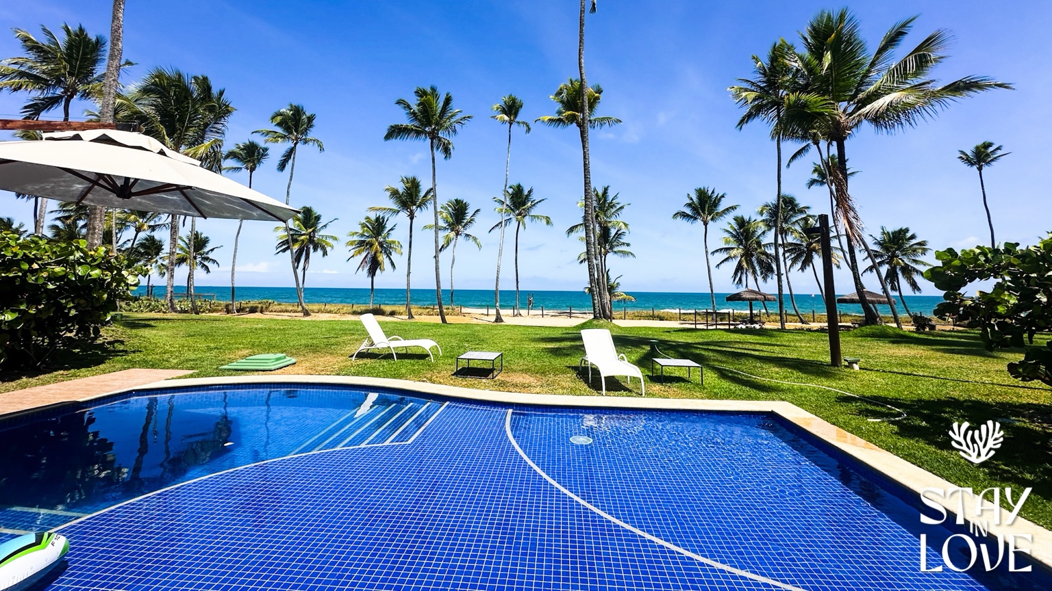 Piscina, jardim com palmeiras e vista para o mar da casa em Ipojuca, Brasil